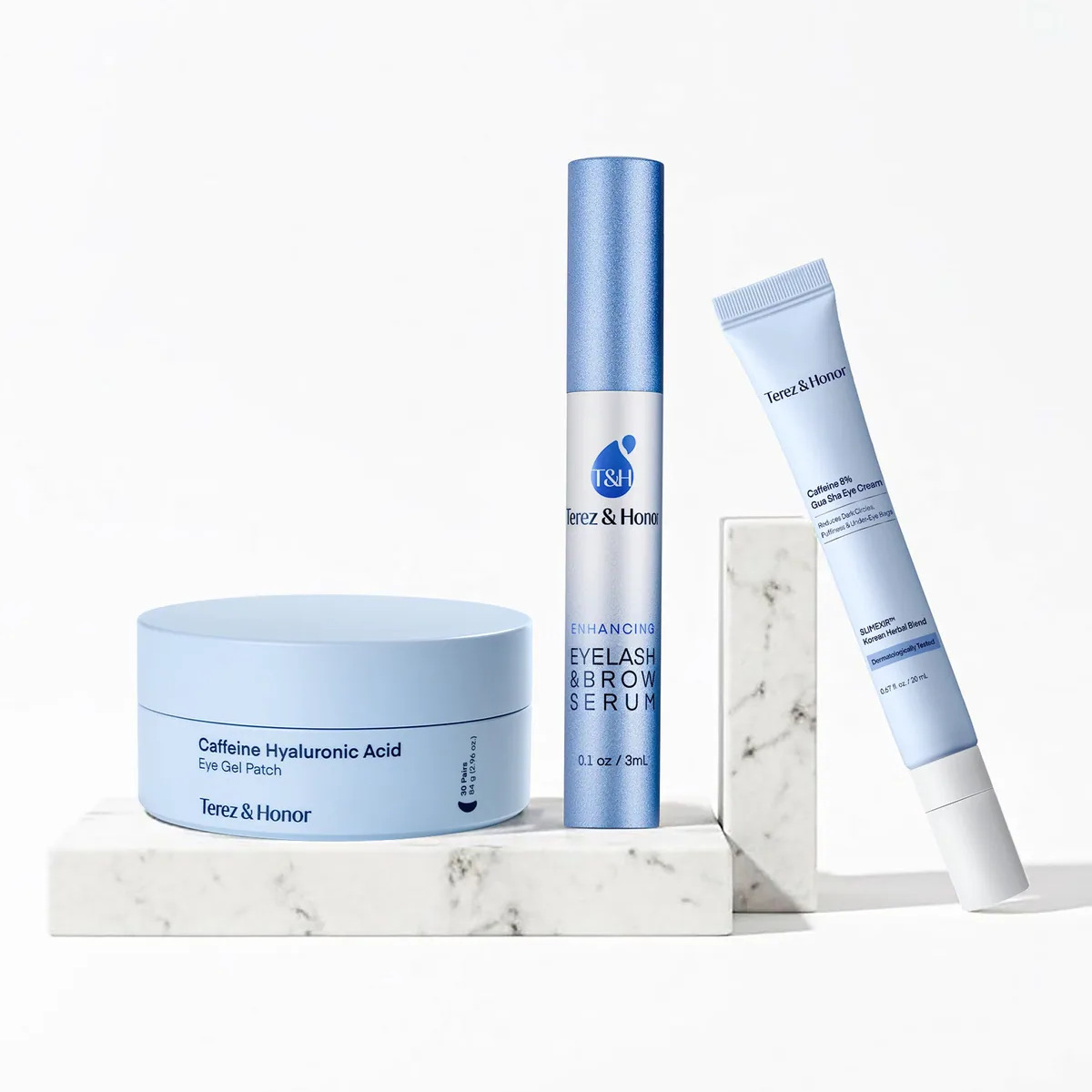 Eye Love Me Set — caffeine hyaluronic eye gel patches, enhancing eyelash and brow serum, and caffeine 8% gua sha eye cream on a marble shelf